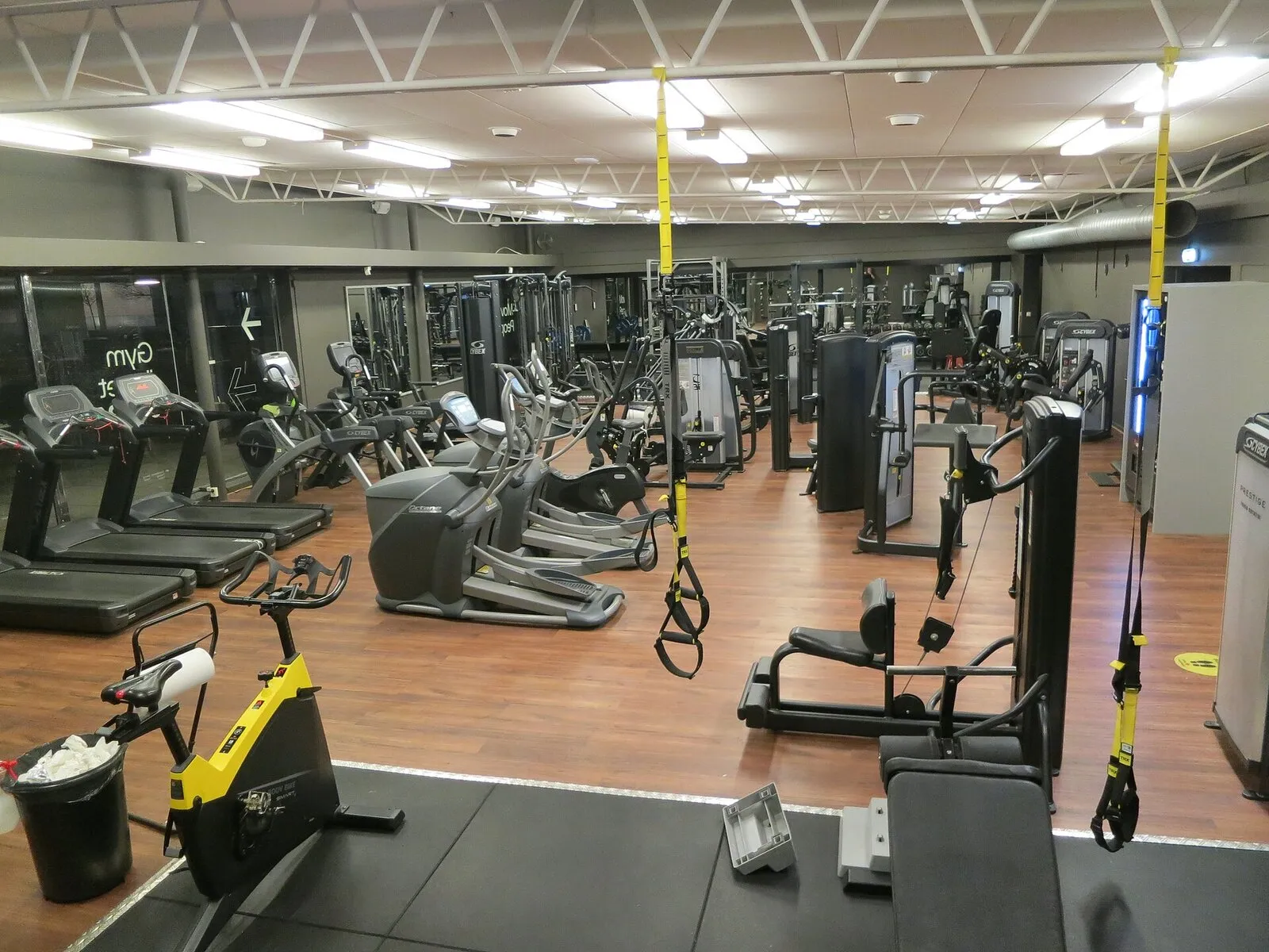 Sala attrezzi di un health club vuota, con tapis roulant, ellittiche, macchine isotoniche e cinghie da sospensione