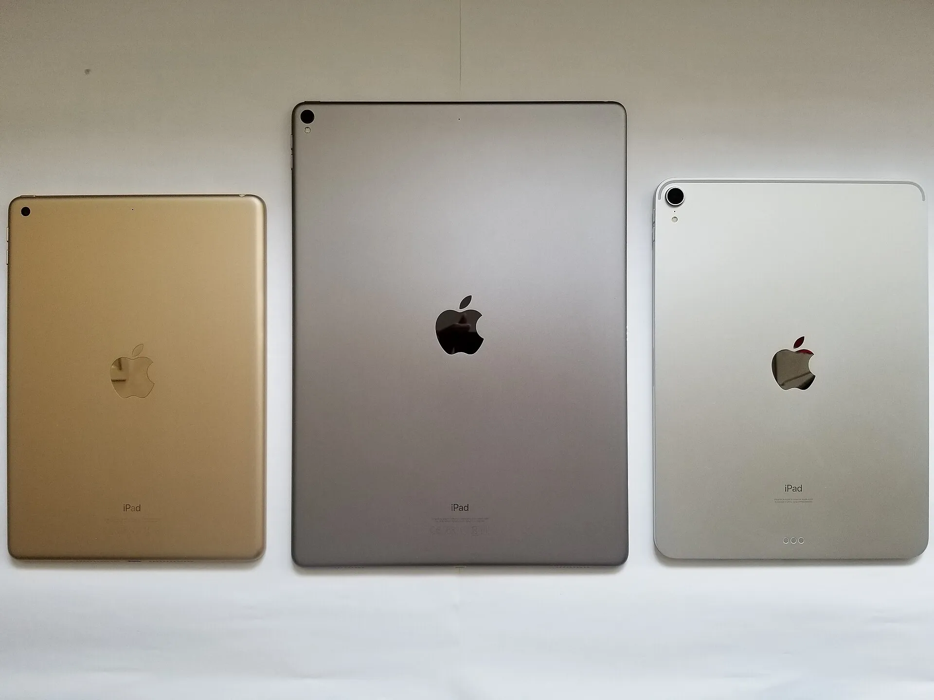 Tre iPad di dimensioni diverse affiancati e visti dal retro, in oro, grigio siderale e argento